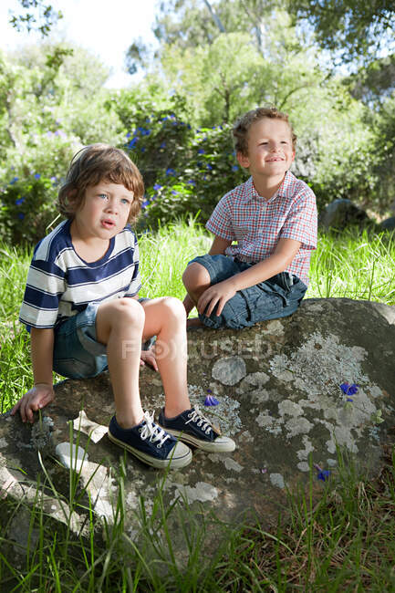 Dos chicos sentados en una roca - foto de stock