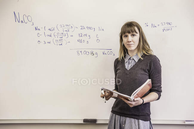 Portrait d'une enseignante devant un tableau blanc lors d'une leçon de lycée — Photo de stock