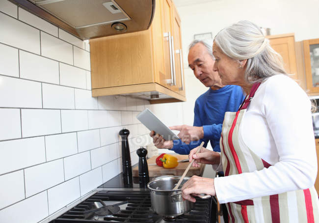 Пожилая пара готовит вместе на кухне — стоковое фото