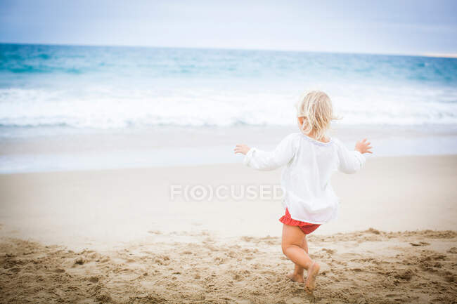 Вид ззаду дівчина біжить до моря — стокове фото