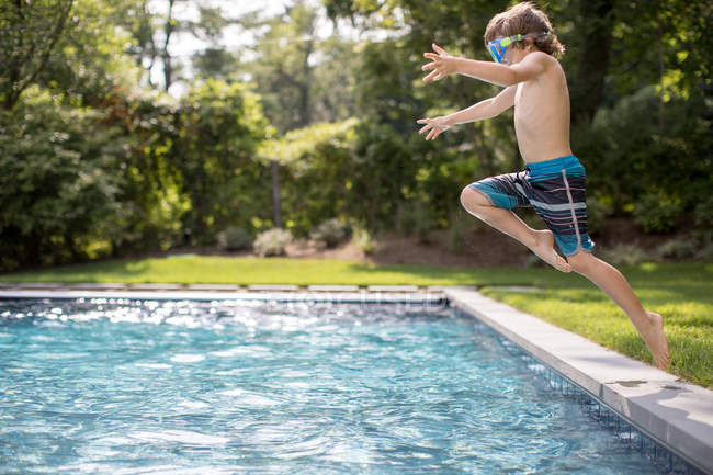 Garçon sauter dans la piscine extérieure — Photo de stock