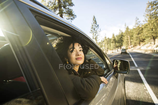 Jeune femme regardant par la fenêtre de la voiture en mouvement — Photo de stock