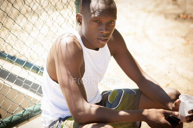 Portrait de jeune joueur de basket masculin avec smartphone et eau potable — Photo de stock