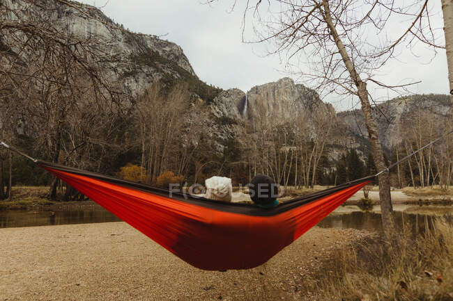 Rear view of couple reclining in red hammock looking out at landscape, Yosemite National Park, California, USA — Stock Photo