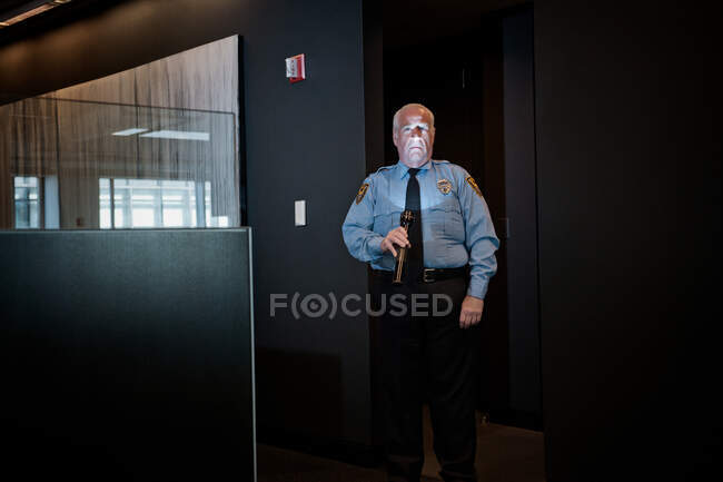 Security guard illuminating face with torch — Stock Photo