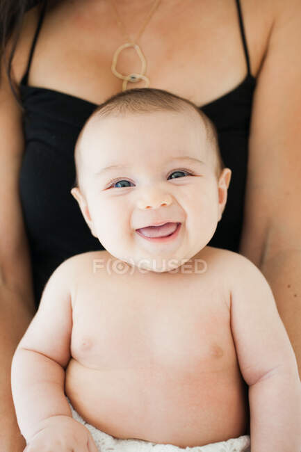 Portrait of smiling baby girl on mother's lap — Stock Photo