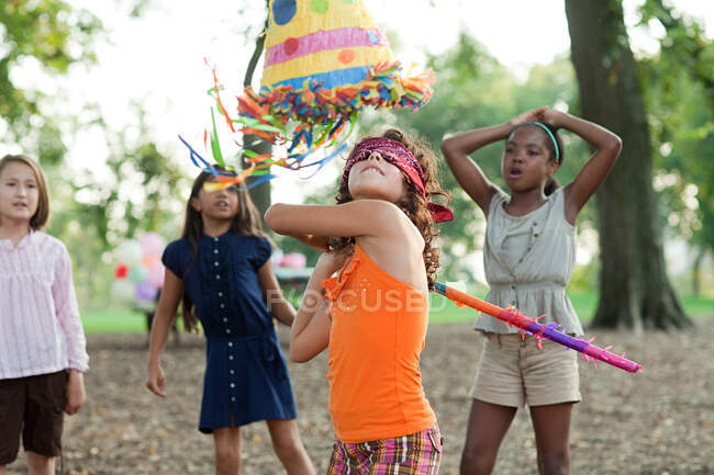 Menina na festa de aniversário batendo pinata — Fotografia de Stock