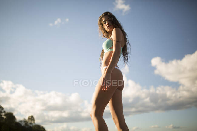 Retrato en ángulo bajo de una mujer joven con el pelo largo en bikini en la costa, Santa Rosa Beach, Florida, EE.UU. - foto de stock