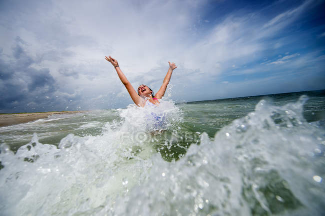 Дівчина стрибає з радістю в океанічній хвилі — стокове фото