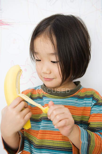 Un garçon épluchant une banane — Photo de stock