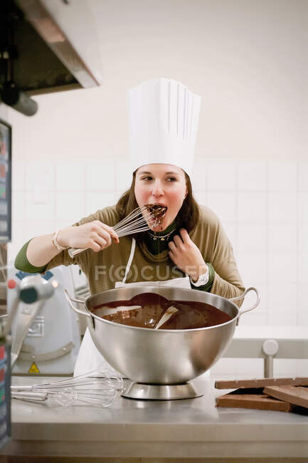 Baker licking whisk in kitchen — Stock Photo