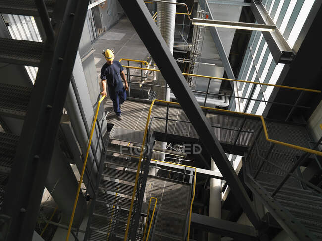 Worker climbing staircase in factory — Stock Photo