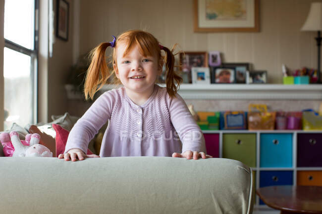 Portrait of young girl with red hair, leaning on sofa — Stock Photo