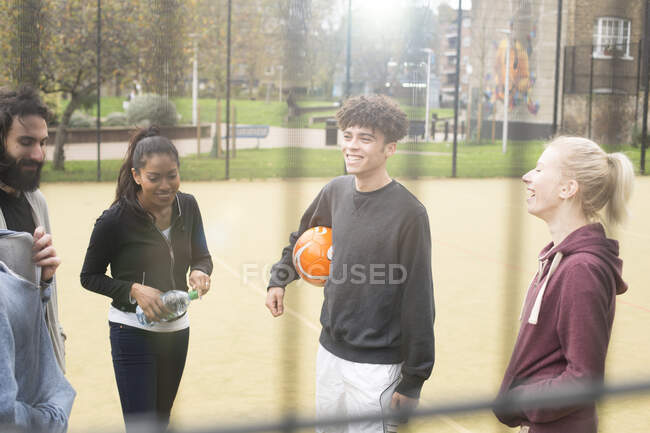 Grupo de adultos em pé em campo de esportes urbanos, conversando — Fotografia de Stock