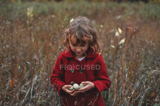 Girl holding wildflower pods in field of long grass — Stock Photo