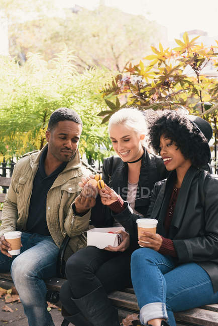 Friends sitting side by side on park bench — Stock Photo