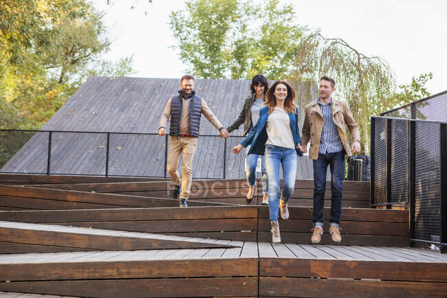 Mid adult couples holding hands on steps — Stock Photo