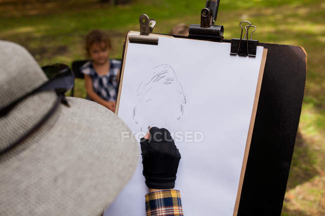 Frau skizziert Porträt eines kleinen Mädchens im Hintergrund — Stockfoto
