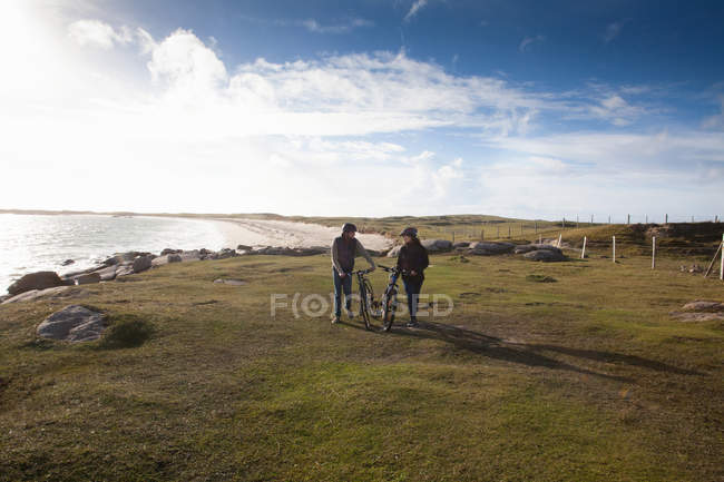 Couple walking with bicycles by the coast, Connemara, Ireland — Stock Photo