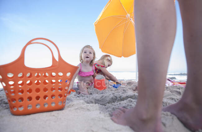 Cidade do Cabo, África do Sul, duas crianças sentadas debaixo do guarda-chuva junto à praia enquanto o adulto está ao seu lado — Fotografia de Stock