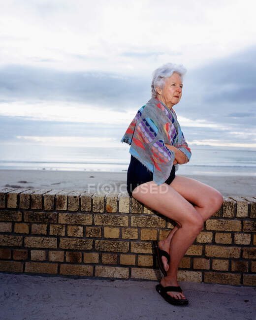Una donna matura seduta vicino al mare — Foto stock