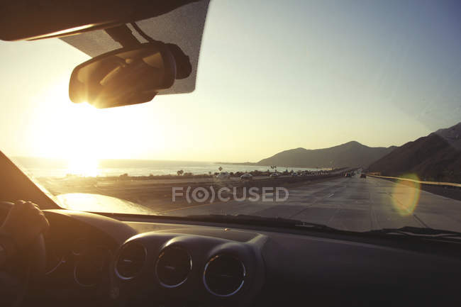 Giovane donna sulla strada guida Pacific Coast Highway al tramonto, California, Stati Uniti — Foto stock