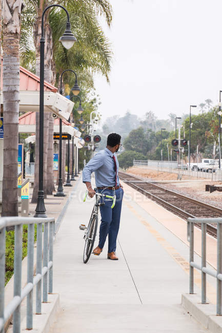 Jovem empresário ciclista olhando para trás da plataforma da estação ferroviária — Fotografia de Stock