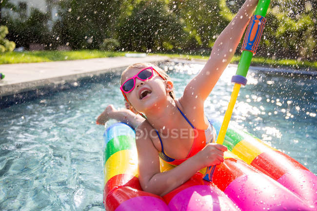 Девушка в бикини на надувной игре с водяным пистолетом в открытом бассейне — стоковое фото