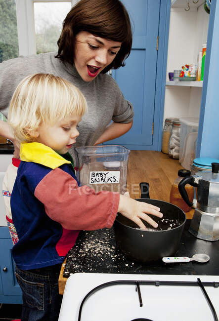 Mother and son making porridge in kitchen — Stock Photo