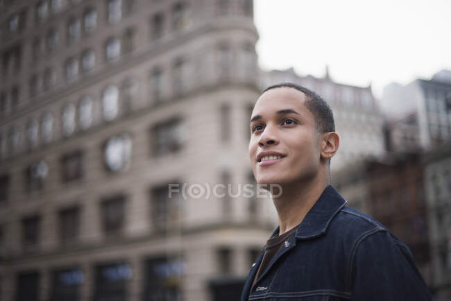 Young man standing in street, Flatiron Building in background, Manhattan, New York, USA — Stock Photo