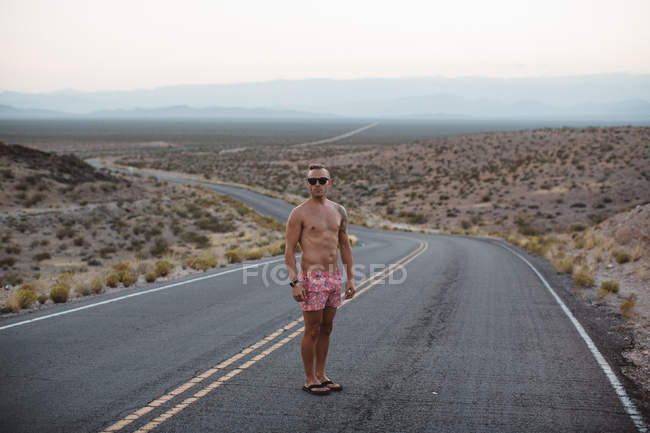 Man wearing and boxer shorts standing on rural road, Valley of Fire State Park, Nevada, USA — Stock Photo