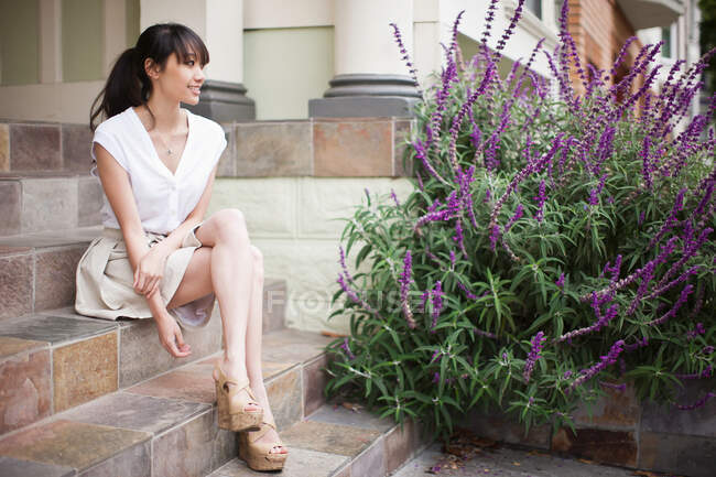 Портрет молодой девушки, сидящей на ступеньках дома — стоковое фото