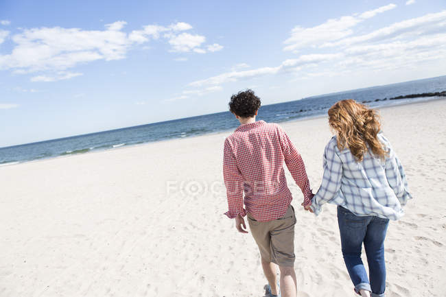 Romantic couple strolling hand in hand on beach — Stock Photo