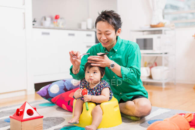 Padre cortando el pelo del bebé en el suelo - foto de stock