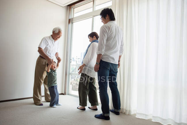 Família de três gerações em pé à janela — Fotografia de Stock