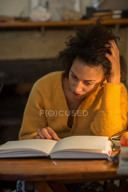 Donna che legge il libro alla scrivania — Foto stock