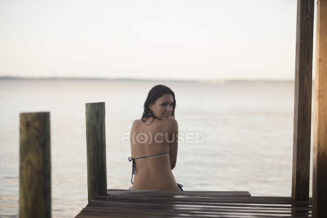 Portrait of mid adult woman in bikini looking back on pier, Santa Rosa Beach, Florida, USA — Stock Photo