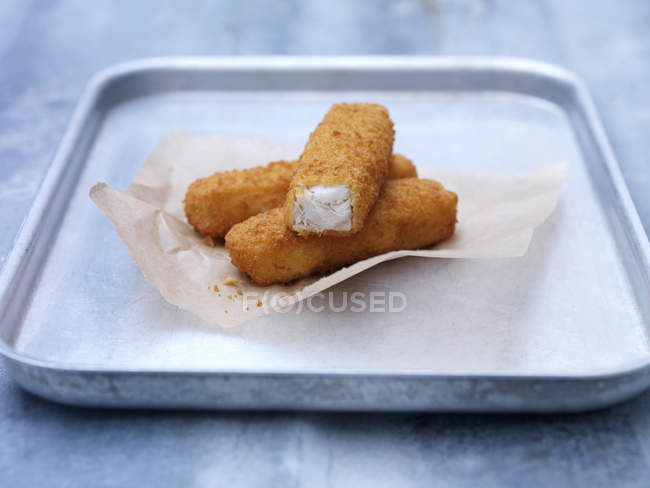 Baking tin with fried chunky breaded fish fingers on steel table — Stock Photo