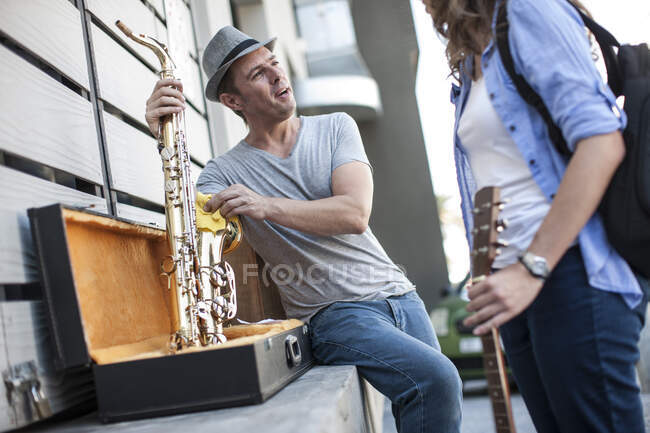 Cape Town, South Africa, yoing man packing away his saxaphone while chatting with his band member — Stock Photo