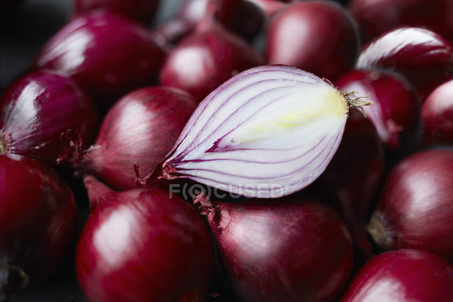 Fresh whole red onions and one halved on table — Stock Photo