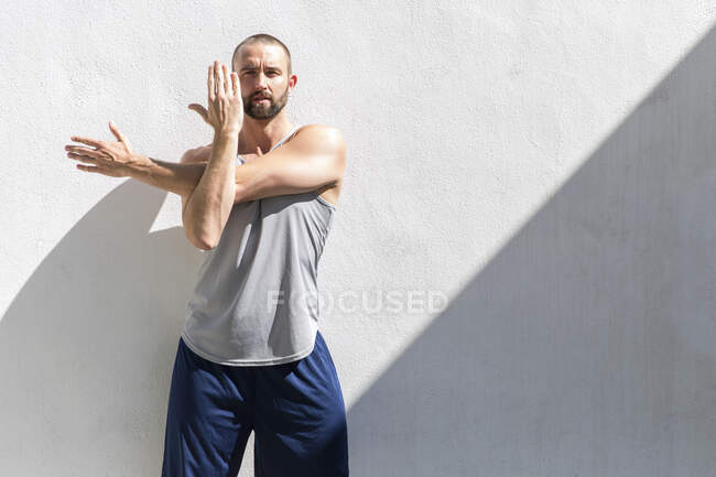 Mid adult man training stretching his arms on patio — Stock Photo