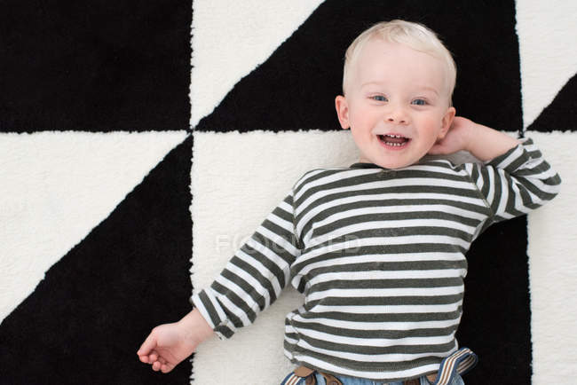 Porträt eines kleinen Jungen, der lächelnd auf dem Boden liegt — Stockfoto