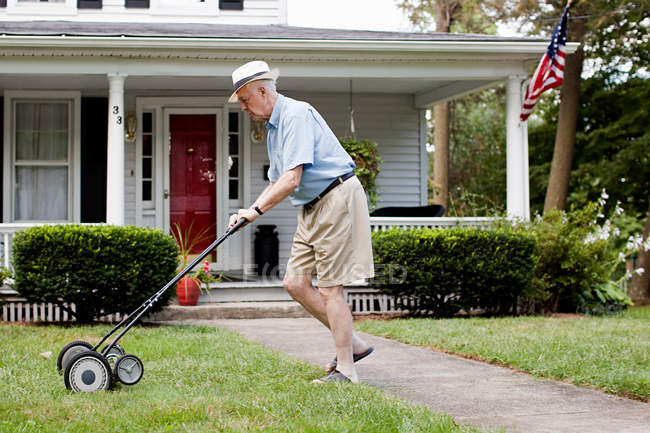 Senior homme tondre sa pelouse devant — Photo de stock