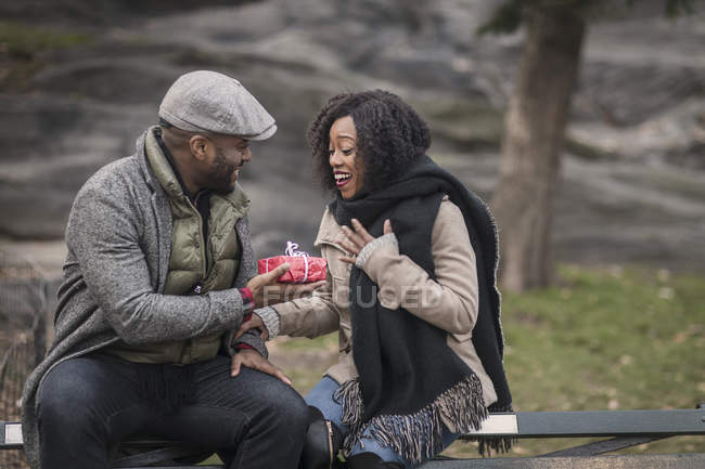 Romántica pareja feliz disfrutando de la ciudad durante las vacaciones de invierno con regalos en el parque - foto de stock