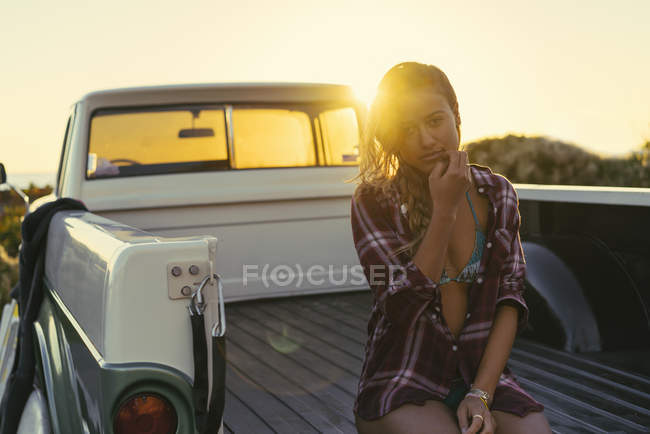 Portrait of young female surfer in back of pickup truck at Newport Beach, California, USA — Stock Photo