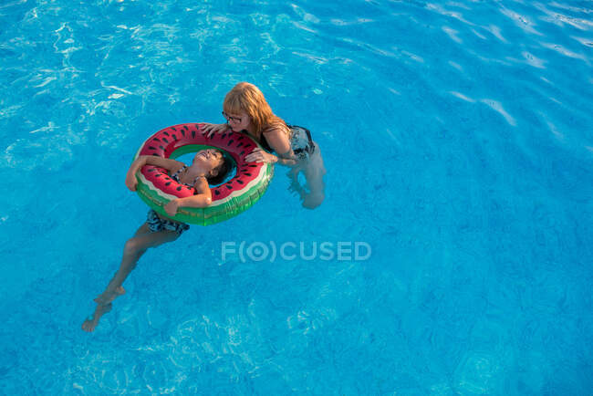 Mother and daughter holding onto inflatable ring in swimming pool — Stock Photo