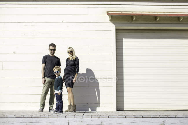 Батьки і хлопчик біля дерев'яної будівлі — стокове фото