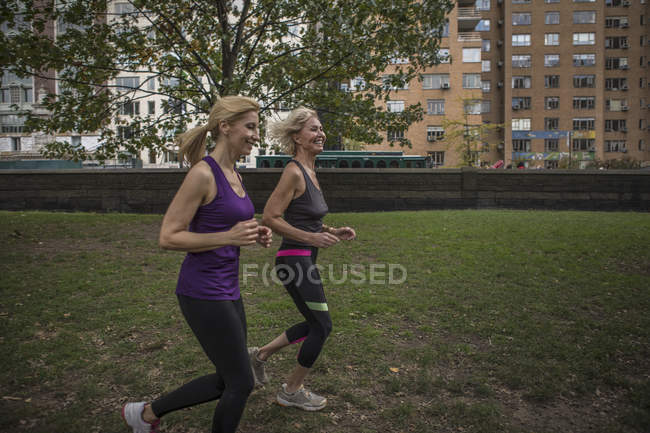 Dos amigas maduras corriendo juntas en el parque - foto de stock