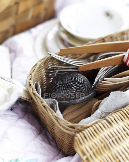 Close up of kitchen utensils and cutlery in wicker picnic basket — Stock Photo
