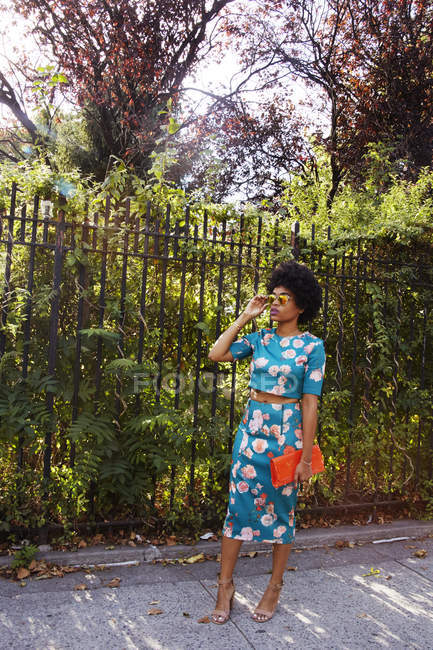 Junge weibliche Mode-Bloggerin mit Afro-Haaren wartet auf dem Bürgersteig des Parks, New York, USA — Stockfoto